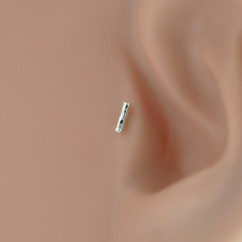 silver bar tragus and helix earring made from bioflex. This unique design adds a touch of edge to your look while ensuring maximum comfort for sensitive ears