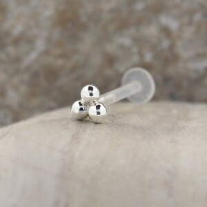 Peut inclure: Bague de nez en argent avec trois boules et une tige en plastique transparente.