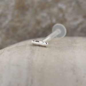 Minimalist tragus and helix earring in classic silver, made from bioflex. Its sleek design offers a stylish option for layering with other ear jewelry.