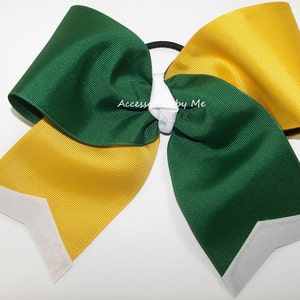 May include: Green and gold cheer bow with white glitter accents. The bow is tied with a white elastic band.