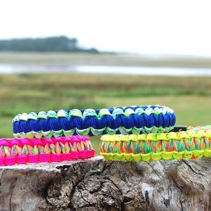 Puede incluir: Tres pulseras de paracord trenzado con combinaciones de colores vibrantes. Una pulsera es rosa neón con un núcleo multicolor, una es azul real con un núcleo verde lima y blanco, y una es amarillo neón con un núcleo multicolor.