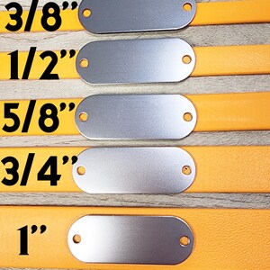 May include: Five silver oval-shaped metal tags with holes on either side, attached to orange leather straps. The tags are labelled with the following sizes: 3/8", 1/2", 5/8", 3/4", and 1".