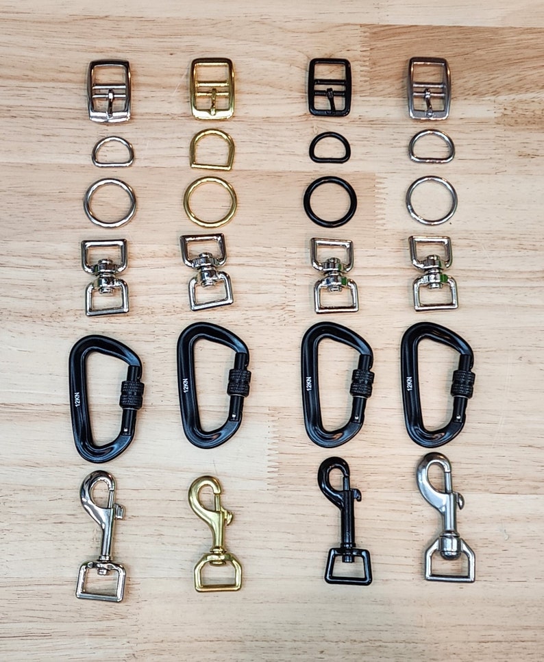 May include: Assortment of metal hardware, including buckles, rings, swivels, carabiners, and hooks in silver, gold, and black finishes.