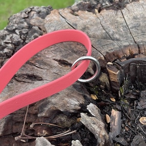 May include: A pink dog collar with a silver metal D-ring. The collar is made of a soft, durable material.