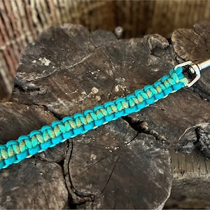 May include: A teal and green paracord keychain with a silver metal clip.