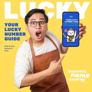 May include: A person wearing glasses and a brown apron points at a smartphone displaying "YOUR LUCKY NUMBER GUIDE." The phone shows a lucky cat illustration with a rainbow and text. The background is yellow with the word "LUCKY" and text "business name energy."
