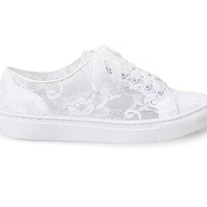 May include: White lace sneakers with a white ribbon tied around the ankle.