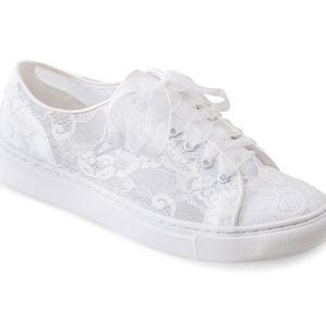 May include: White lace sneakers with a satin ribbon tied around the ankle. The sneakers have a white rubber sole.