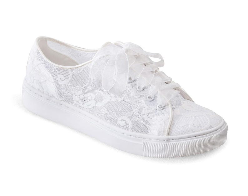 May include: White lace sneakers with a satin ribbon tied around the ankle. The sneakers have a white rubber sole.