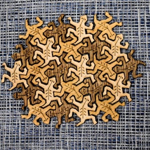 May include: A wooden puzzle featuring a circular design of interlocking figures. The figures are stylized human shapes with arms and legs, and they are arranged in a repeating pattern. The puzzle is made of light and dark wood, creating a contrasting effect.
