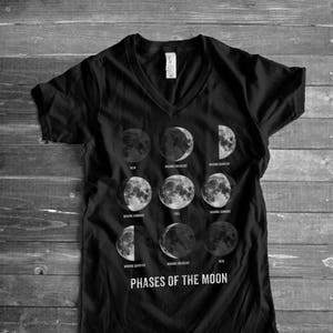 May include: Black v-neck t-shirt with a graphic of the phases of the moon. The text "PHASES OF THE MOON" is printed below the graphic.
