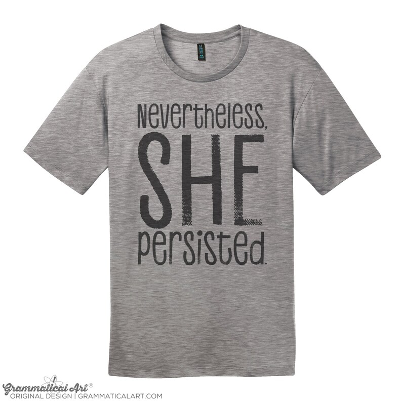 May include: A heather grey t-shirt with the text "Nevertheless, SHE persisted." printed in black.