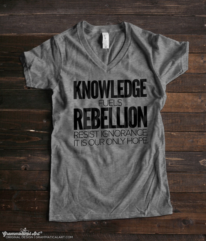 Puede incluir: Camiseta gris de cuello en V con texto negro que dice "Knowledge fuels rebellion. Resist ignorance. It is our only hope."