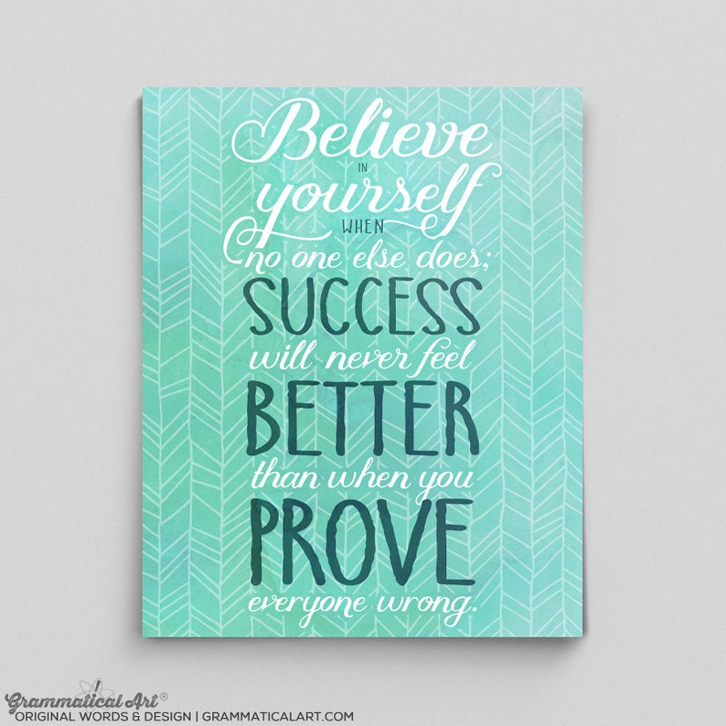 May include: A motivational art print with a teal background and white chevron pattern. The artwork features the quote "Believe in yourself when no one else does; success will never feel better than when you prove everyone wrong."