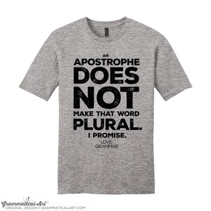 May include: A gray t-shirt with black text that reads "An Apostrophe Does Not Make That Word Plural. I Promise. Love Grammar".