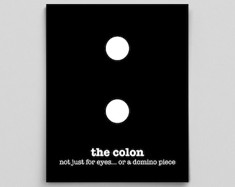 May include: Black and white graphic print with two white circles representing a colon punctuation mark. The text below reads "the colon not just for eyes... or a domino piece".
