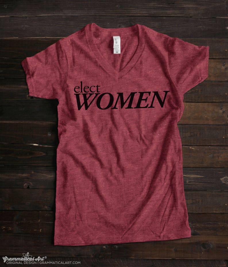 May include: A maroon v-neck t-shirt with the text "elect WOMEN" printed in black.
