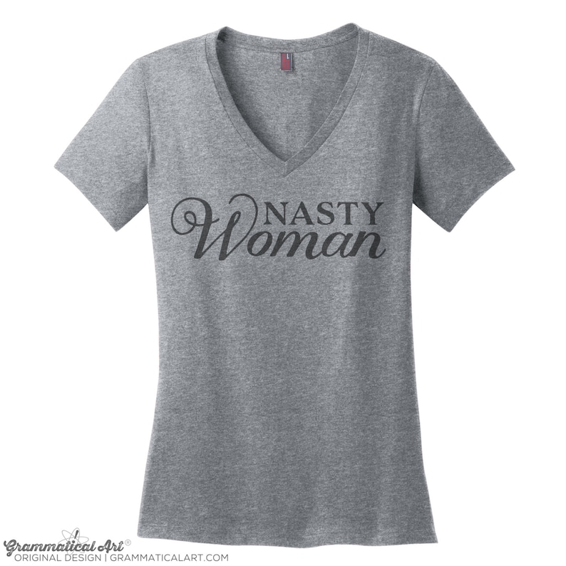 May include: Gray V-neck t-shirt with the text "Nasty Woman" in a black cursive font.