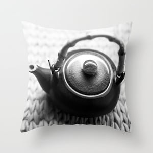Puede incluir: Foto en blanco y negro de una tetera de cerámica con asa de bambú, sobre una estera tejida.