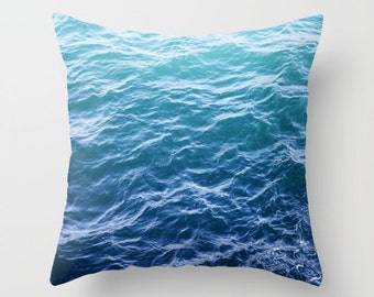 May include: A throw pillow featuring a close-up image of blue ocean waves. The pillow has a soft, textured fabric and is perfect for adding a touch of coastal style to any room.