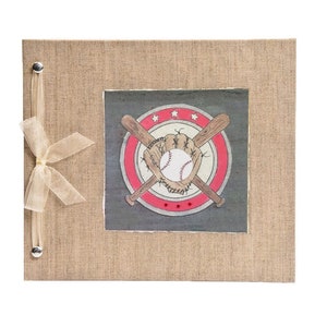 May include: A baseball-themed scrapbook with a burlap cover. The center features a baseball, glove, and crossed bats design within a red and white circle. A sheer ribbon and silver stud closure add a decorative touch.