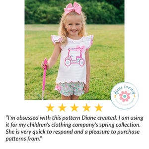 May include: A white short-sleeved shirt with a pink golf cart graphic and a pink bow, paired with floral print shorts featuring a ruffled hem. The outfit includes a large pink hair bow and a pink accessory held in one hand.
