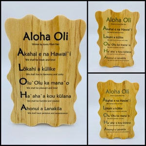 May include: Three wooden plaques with the Hawaiian phrase "Aloha Oli" and a set of verses in English and Hawaiian. The plaques are light brown with a wood grain pattern. The text is in black and green.