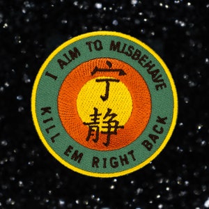 May include: Embroidered patch with the text "I AIM TO MISBEHAVE KILL EM RIGHT BACK" in a circular design. The patch features a green outer ring, an orange middle ring, and a yellow center with Asian characters.