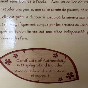 May include: A brown leaf-shaped certificate of authenticity with white text that reads "Certificate of Authenticity & Display Stand Included. Avec certificat d'authenticit&eacute; et support."