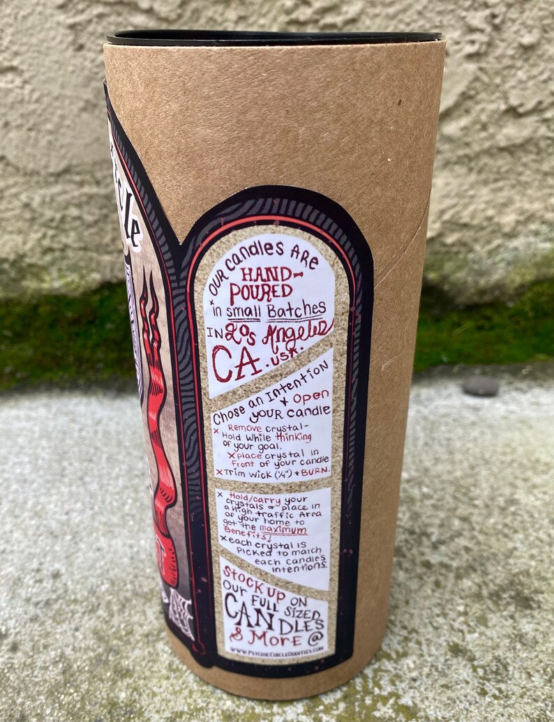 Pode incluir: Um tubo de cart&atilde;o castanho com um r&oacute;tulo preto que apresenta uma ilustra&ccedil;&atilde;o vermelha e preta de uma vela. O r&oacute;tulo inclui o texto "Nossas velas s&atilde;o feitas &agrave; m&atilde;o em pequenos lotes em Los Angeles, Calif&oacute;rnia." e instru&ccedil;&otilde;es para usar a vela com cristais. O r&oacute;tulo tamb&eacute;m inclui o texto "Abaste&ccedil;a-se de nossas velas de tamanho completo e mais @ www.psychiccirclecandles.com".