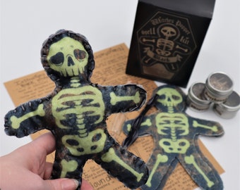 May include: Two green and black skeleton voodoo dolls with stitched seams. The dolls are lying on a brown paper surface with text that reads "Mugwort + reverse" and "Lound".