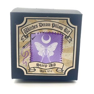 May include: A black box with a vintage-style label that reads "Witches Dream Pillow Kit Sleep Aid Ages 10+". The label features a purple pillow with a crescent moon and a white moth embroidered on it.
