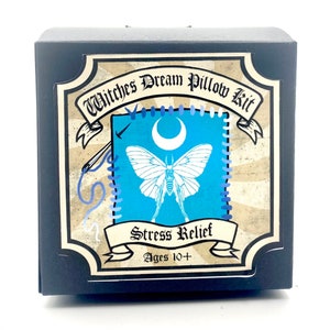 May include: A black box with a label that says "Witches Dream Pillow Kit" and features a blue background with a white moth and crescent moon. The label also says "Stress Relief" and "Ages 10+".