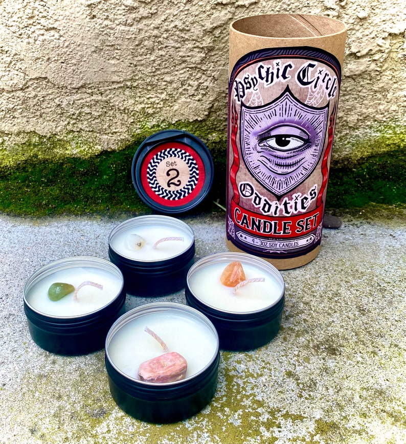 Pu&ograve; includere: Set di quattro piccole candele in barattoli neri con un singolo cristallo incorporato in ciascuno. Le candele sono etichettate "Psychic Circle Oddities Candle Set" e "1 - 3oz Soy Candles".