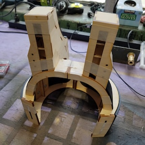 Puede incluir: Un marco de madera con un forro de tela negro, posiblemente para un auricular de realidad virtual. El marco está hecho de varias piezas de madera, unidas con cinta adhesiva.