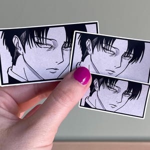 May include: Black and white stickers featuring an anime-style illustration of a character with dark hair and a serious expression. The stickers are rectangular with a white border and are held against a neutral background.