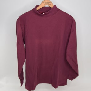 Puede incluir: Una camisa de cuello alto de manga larga de color burdeos.