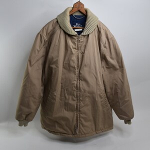 May include: A tan quilted jacket with a zipper closure and a ribbed knit collar. The jacket has a blue label with the text "Weatherproof" on the front.