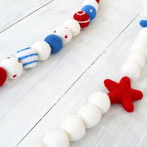 May include: A red, white, and blue felt garland with stars and stripes. The garland is made of felt balls and stars.