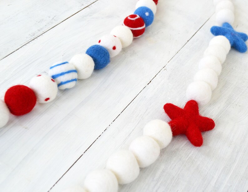 May include: A red, white, and blue felt garland with stars and stripes. The garland is made of felt balls and stars.