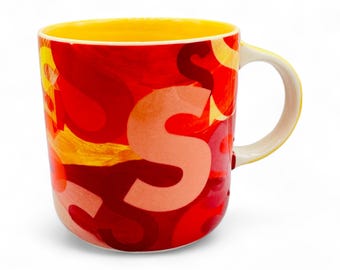 Levendige gele en rode antropologie-koffiemok met 'S'-monogram