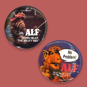 Può includere: Due bottoni rotondi con il personaggio ALF. Un bottone presenta ALF con un microfono e la scritta "Born Near The Milky Way". L'altro bottone mostra ALF con un fumetto che dice "No Problem!" e il logo ALF.