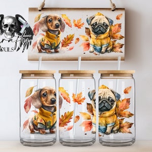 May include: Glass tumblers with bamboo lids and straws, decorated with watercolour illustrations of a dachshund and a pug in yellow jackets, surrounded by autumn leaves. A wooden sign with the same design.