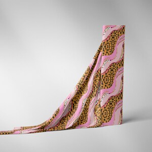 May include: A pink and brown fabric with a leopard print and wavy lines. The fabric is draped over a white surface.
