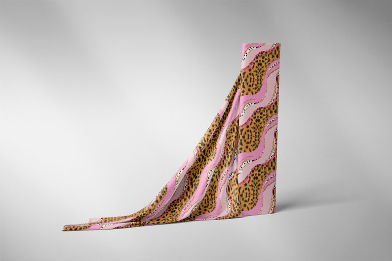 May include: A pink and brown fabric with a leopard print and wavy lines. The fabric is draped over a white surface.