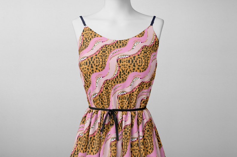 May include: A sleeveless dress with a pink and brown leopard print pattern. The dress has a black ribbon tie at the waist.