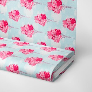 May include: A blue fabric with a repeating pattern of pink heart-shaped balloons. The fabric is folded and rolled up.
