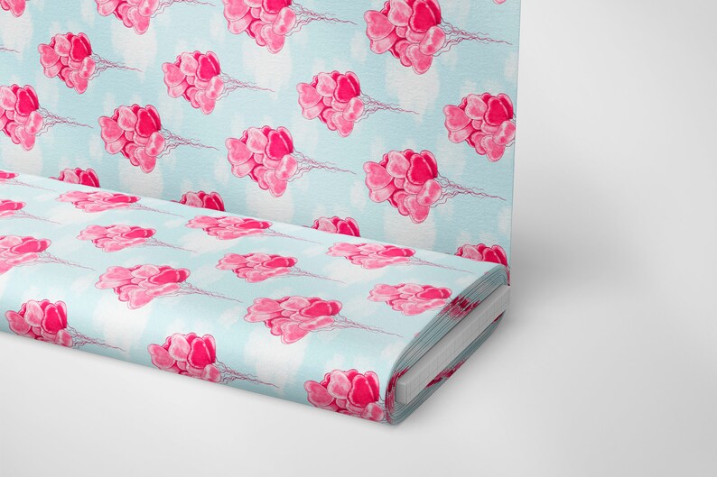 May include: A blue fabric with a repeating pattern of pink heart-shaped balloons. The fabric is folded and rolled up.