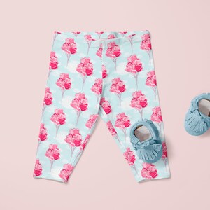 May include: Baby leggings with a light blue background and a pink heart balloon pattern. The leggings are paired with blue suede baby shoes.