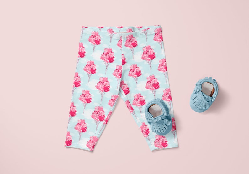 May include: Baby leggings with a light blue background and a pink heart balloon pattern. The leggings are paired with blue suede baby shoes.